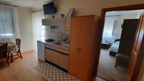 Un espace de vie compact comprenant un coin cuisine, un coin repas et une chambre.