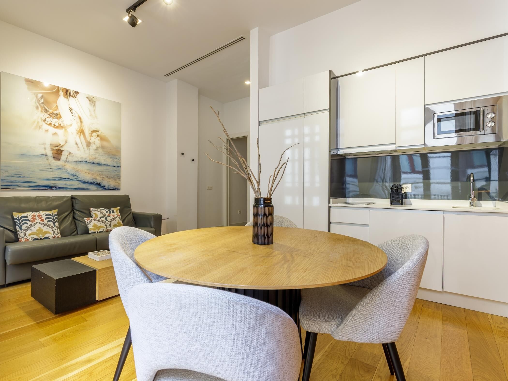 A modern kitchen with white cabinets, a microwave, and a coffee machine.