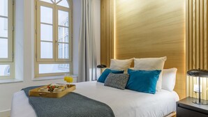 Una habitación de hotel moderna con una cama grande, un cabecero de madera y una ventana con cortinas.