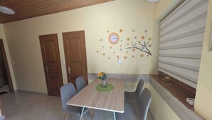 A dining area with a wooden table, grey chairs, and a wall clock. - Holiday apartment with large terrace, air conditioning and WiFi (Balatonboglár)