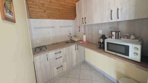 A compact kitchen with wooden cabinets, a microwave, and a coffee maker. - Holiday apartment with large terrace, air conditioning and WiFi (Balatonboglár)