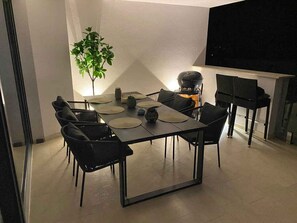 Uma zona de refeições moderna com uma mesa retangular, cadeiras pretas e um vaso de planta.