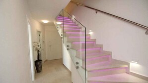 Eine moderne Treppe mit Glasgeländern und beleuchteten Stufen.