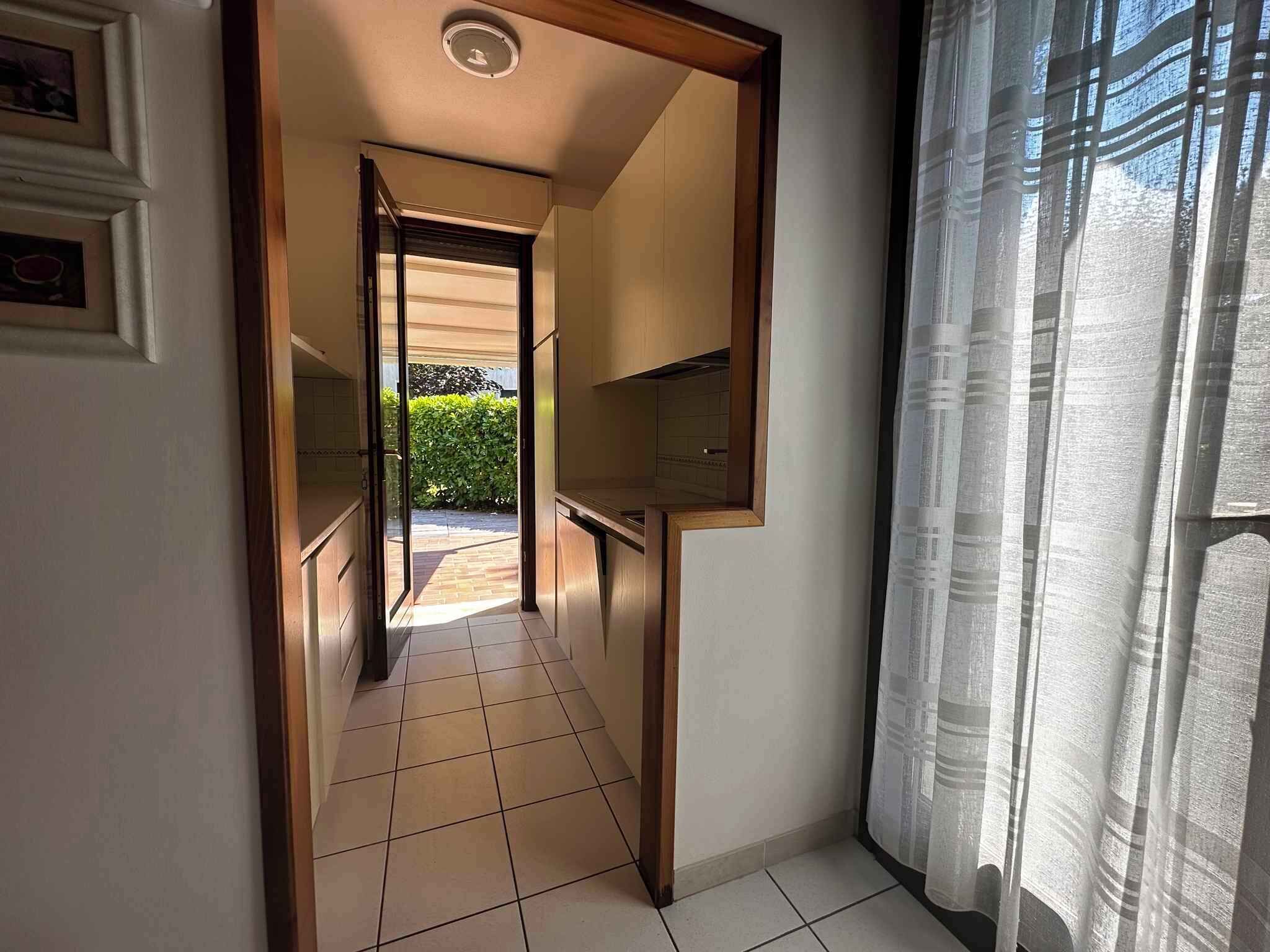 Un pasillo estrecho con suelo de baldosas que conduce a una puerta.