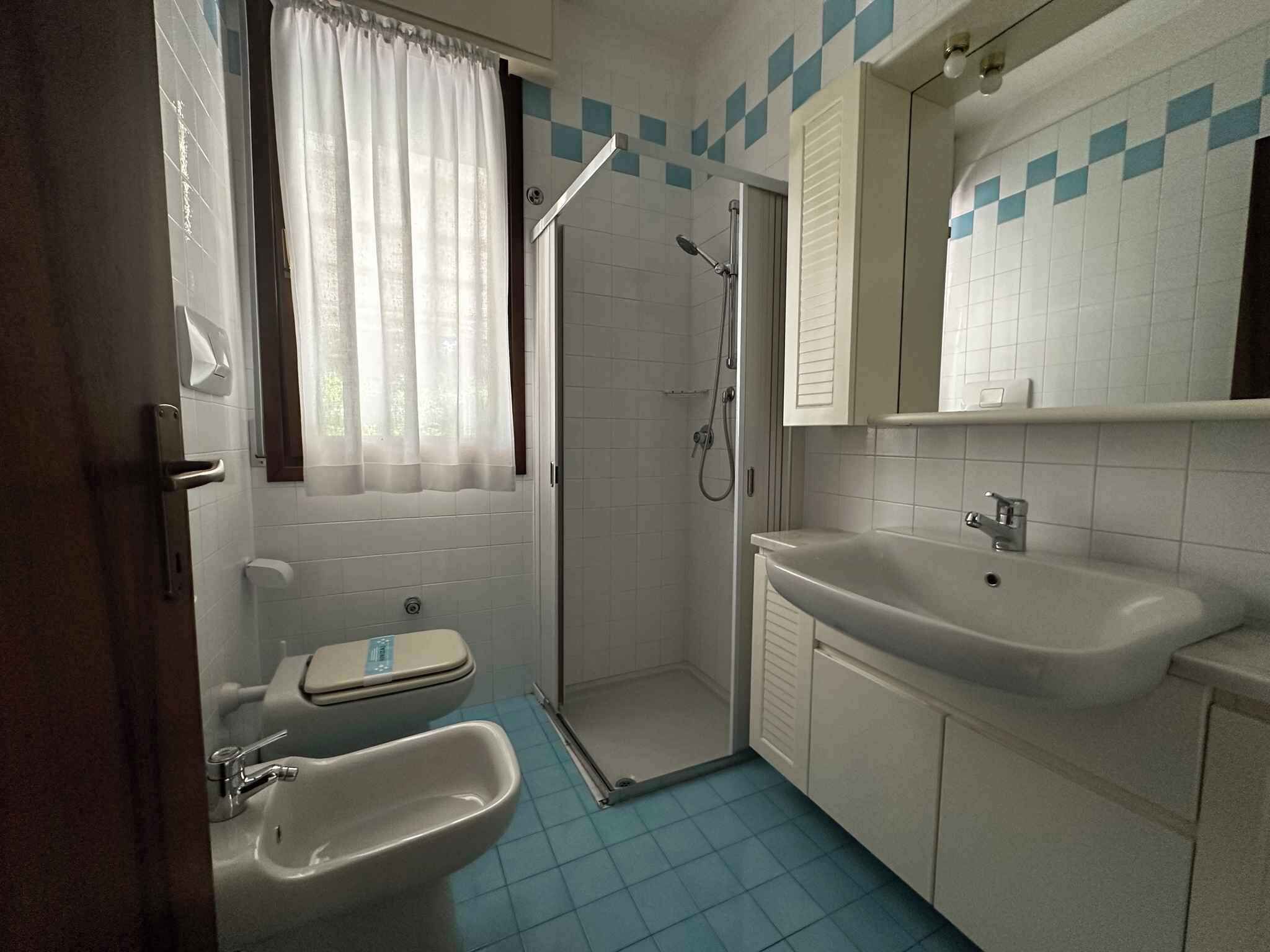 A bathroom with a shower, toilet, sink, and a mirror.