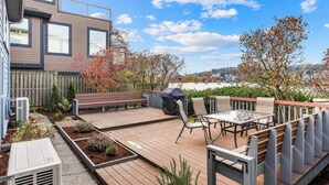 Een terras met tuinmeubilair, een houten omheining en uitzicht op een stadsgezicht.