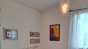 A bedroom with a bed, a bedside table, a hanging light fixture, and framed pictures on the wall. - Holiday apartment with private garden in a quiet location (Bibione)