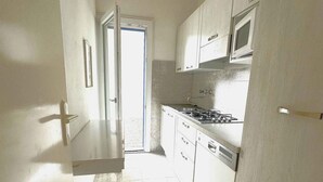 Een keuken met witte kastjes, een magnetron en een fornuis.