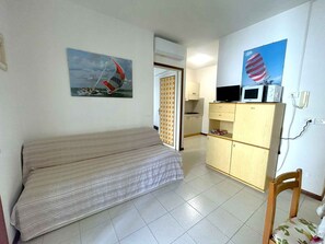 A compact room with a bed, a kitchenette, and a dining area. - Holiday apartment near the sea (Bibione)
