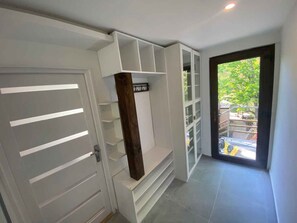 Ein modernes Interieur mit Einbauschränken, einer Tür mit horizontalen Lamellen und Blick ins Freie durch eine Glastür.
