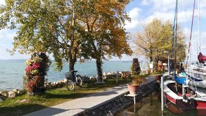 Uma passarela à beira do lago com uma bicicleta, um barco atracado à direita e um muro de pedra.