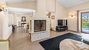 Ein Wohnzimmer mit Kamin aus Stein, einem Fernseher und einem Essbereich mit Tisch und Stühlen.