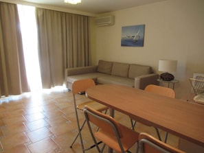 A room with a sofa, a dining table with chairs, a lamp, and a painting on the wall. - Holiday apartment on the Csopak promenade (Csopak)
