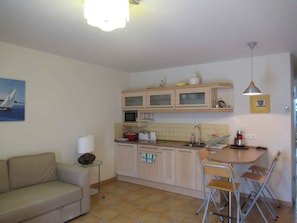 A compact kitchen with a dining area, a sofa, and a painting on the wall. - Holiday apartment on the Csopak promenade (Csopak)