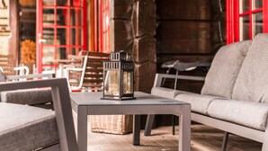 A modern outdoor seating area with a glass-top table, a gray sofa, and a lantern. - 2 bedroom gorgeous apartment in Bjorli (Bjorli)