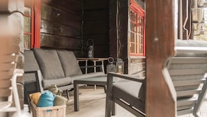 A cozy outdoor seating area with a sofa and chairs, a small table, and a wicker basket with items. - 2 bedroom gorgeous apartment in Bjorli (Bjorli)