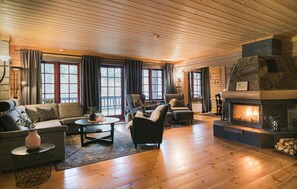 Una sala de estar acogedora con chimenea, pisos de madera y ventanas amplias.