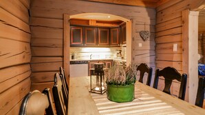 A wooden interior with a dining table, chairs, and a view into the kitchen area. - 2 bedroom gorgeous apartment in Bjorli (Bjorli)