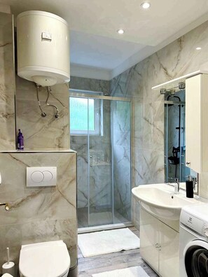 Een moderne badkamer met een douchecabine van glas, een ingebouwd wastafelmeubel en een toilet.