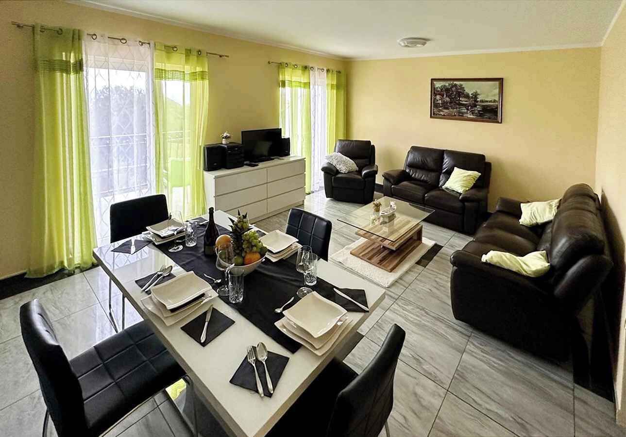 A dining area with a table set for four, two sofas, and a television in the background.