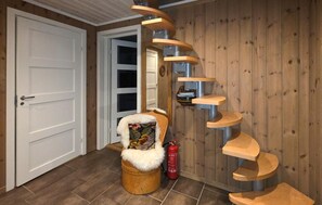 A spiral staircase with wooden steps leading to a landing, a white door, and a small wooden chair with a fur throw. - Cozy home in Rauland with sauna (Rauland)