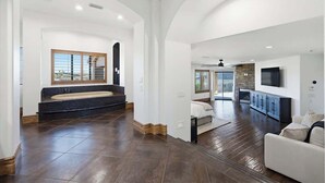 A spacious living area with a large window, a built-in bench, and a flat-screen TV mounted on the wall. - Epic Views | Pool • Spa • RV Garage | Near Marina (Lake Havasu City)