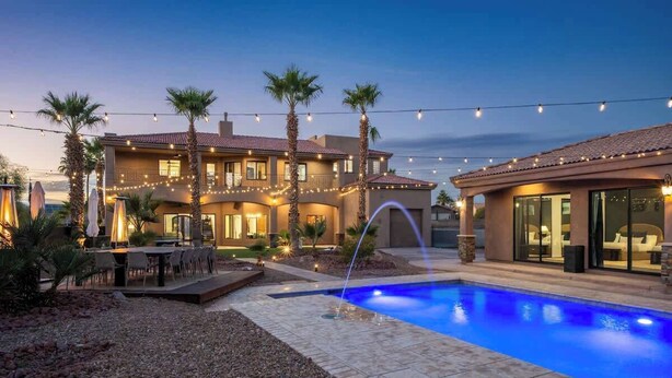 A two-story house with a swimming pool, outdoor seating, and string lights. - Epic Views | Pool • Spa • RV Garage | Near Marina (Lake Havasu City)