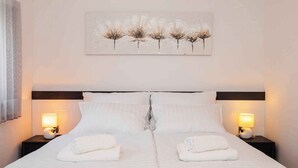 Un letto matrimoniale con lenzuola bianche e due lampade da comodino.