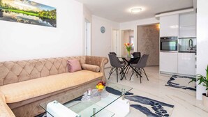 Un soggiorno moderno con un divano color beige, un tavolino in vetro e un'area pranzo con tavolo e sedie.