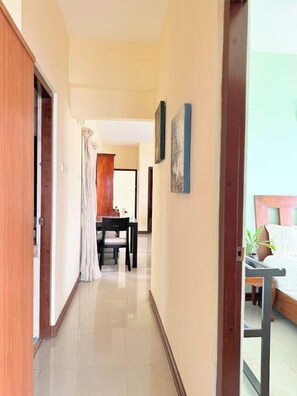 A hotel corridor with a dining area, a bed with a view, and a staircase. - Marine Escape | 3BR Ocean View Beach Apt Sri Lanka (Colombo)