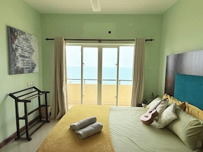 A hotel room with a bed, a guitar, a painting, and a view of the sea. - Marine Escape | 3BR Ocean View Beach Apt Sri Lanka (Colombo)
