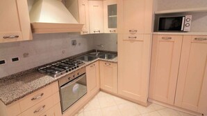 Een keuken met lichte kastjes, een gasfornuis, een magnetron en een spoelbak.