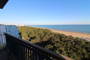 A balcony with a view of a beach and forest. - Holiday flat with air conditioning and balcony with sea view (Lignano Sabbiadoro)