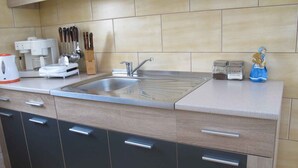 A modern kitchen with a stainless steel sink, a coffee machine, and various utensils. - Holiday home with garden (Malinska)