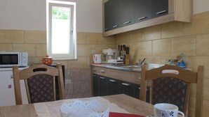 A kitchen with wooden cabinets, a microwave, a coffee maker, and a window. - Holiday home with garden (Malinska)