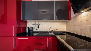 Een moderne keuken met rode kasten, een zwart aanrecht en een ingebouwde kookplaat.