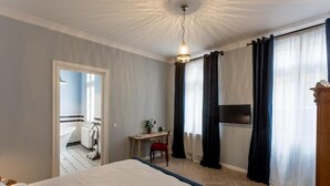 Une chambre d’hôtel avec un lit, un bureau, une chaise, une télévision et une salle de bain visible à travers une porte ouverte.