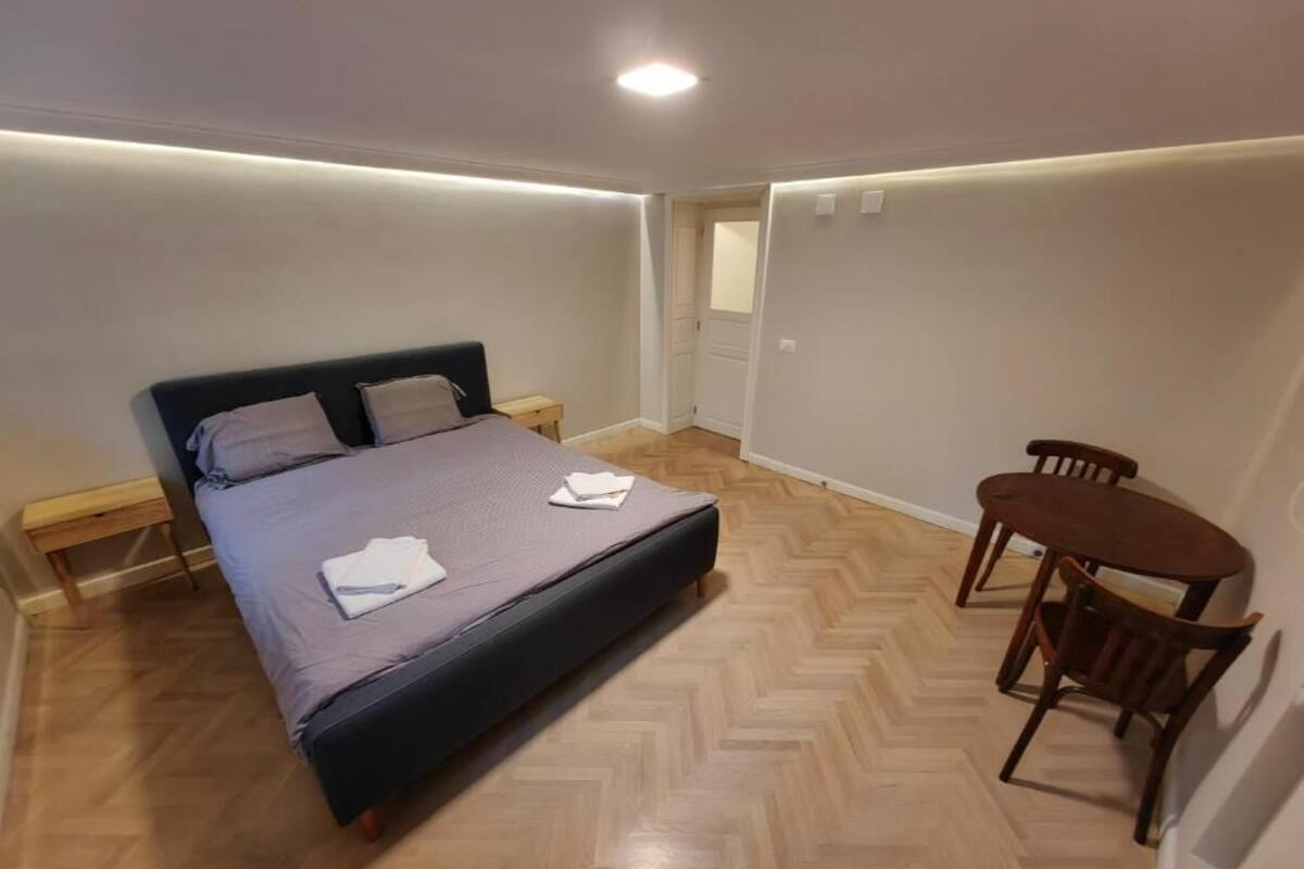 A bedroom with a bed, bedside table, and a small wooden chair.