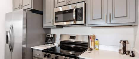 Una cocina moderna con electrodomésticos de acero inoxidable, que incluyen un refrigerador, microondas, estufa y horno.