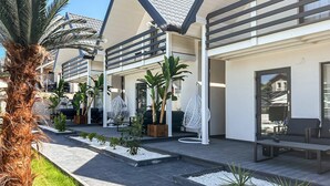 Un edificio moderno con un patio que incluye asientos al aire libre, plantas en macetas y una palmera.