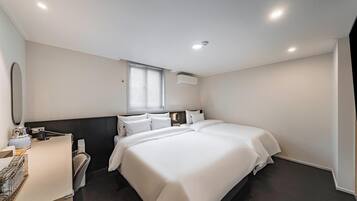 A modern hotel room with a large bed, a bedside table, a mirror, and a window with blinds.
