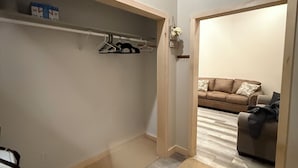 A walk-in closet with hanging space, a shoe rack, and a small seating area with a couch and pillows.