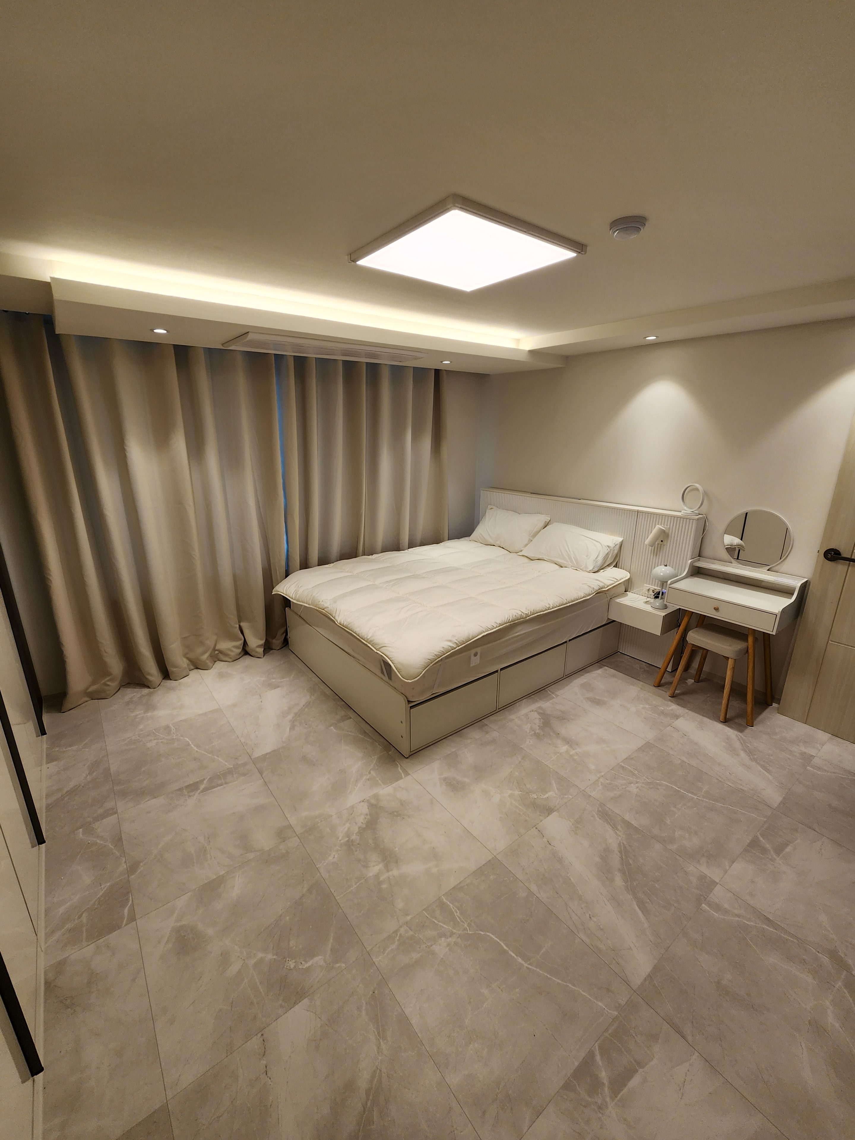 Quarto com cama, escrivaninha e espelho.
