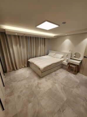 Quarto com cama, escrivaninha e espelho.