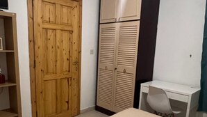 A bedroom with a wooden door, a wardrobe with louvered doors, a white desk, and a chair. - Spacious Room & Shared Bath in Valletta ( Ħamrun)