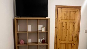A room with a wooden door and a TV on a wooden stand. - Spacious Room & Shared Bath in Valletta (Ħamrun)