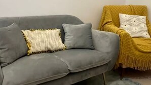 A grey sofa with two cushions, one with yellow beads, and a yellow armchair with a patterned cushion. - Spacious Room & Shared Bath in Valletta (Ħamrun)
