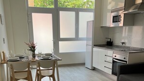 A modern kitchen with a dining area, featuring a large window, a microwave, and a built-in oven.