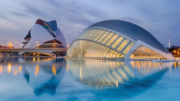 A modern architectural structure with a reflective water surface in front.