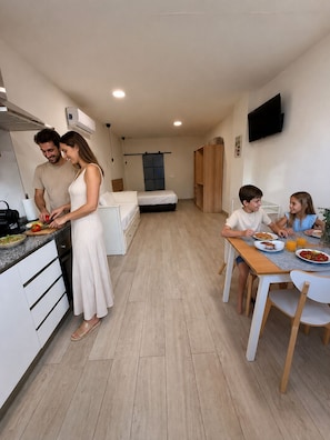 A modern apartment with a kitchen, dining area, and a bedroom with a bed and wardrobe. - Apartamento cómodo cerca del Puerto  (València)